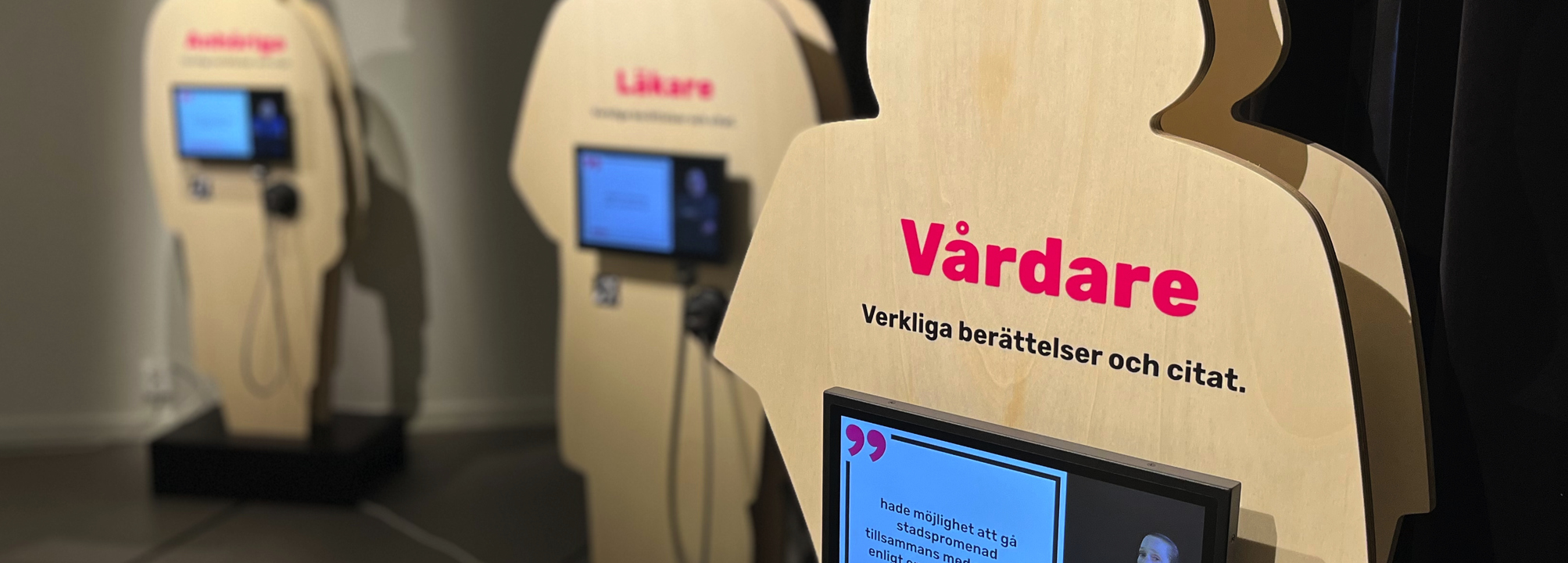 Silhuetter i plywood med skärmar på. Del av en utställning.